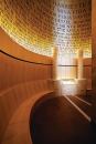 The Room of Remembrance is a double-height 
volume located on the third floor of the museum. Flanked by Jerusalem 
stone columns, a book containing the names of those killed during the 
Holocaust and memories penned by family and community members serves as 
the focal point of the space. Bent-wood, uplit panels were painted with 
names of the dead, in English, Yiddish, and Hebrew. First names were 
used so as to represent as many individuals as possible; the names are 2
 1/2 inches high at the base and increase in size as they move toward 
the ceiling. The names begin in a full, rich black at the base, which 
turns into a mid-tone black at the top. This was a nod to an idea by a 
community member to have smoke coming from behind the book of names, a 
proposal that was not carried out because of fire regulations.