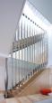 The design for the staircase is centered on folded stainless steel. Hung from a structural steel support on the top level of the townhouse, vertical folded pieces create a continuous screen that encloses the two above-grade flights of stairs. Tabs on the bent risers are fitted into slots on the vertical pieces, which created an easy setup for on-site construction and spot-welding.