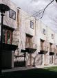Steel balconies, wood windows and doors, and color-through black stucco establish a rhythm on the facade.