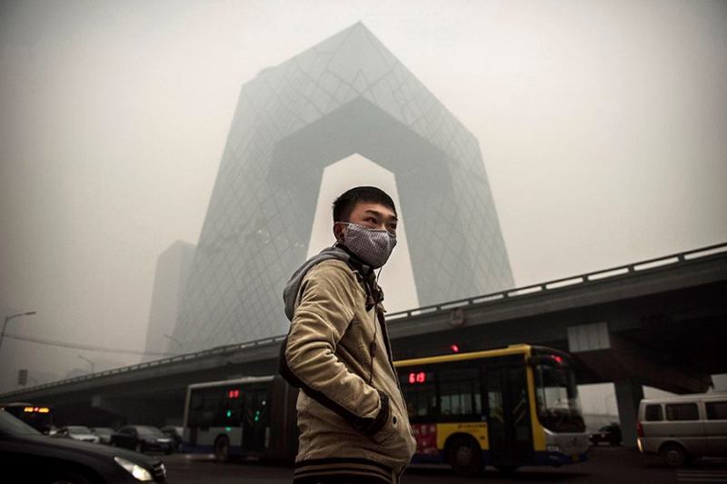 A man wears a mask during heavy smog in Beijing last month. OMA's CCTV building stands in the background.
