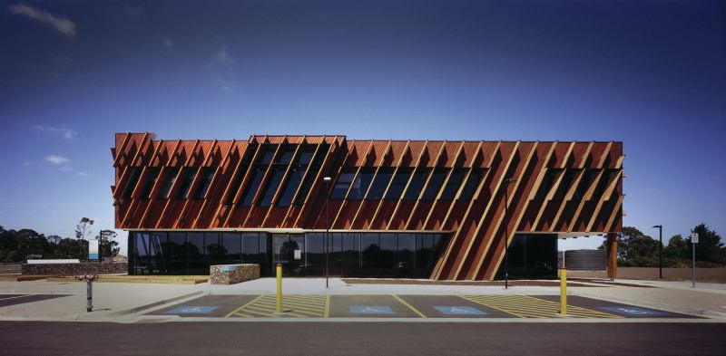 Pre-drilled boards attached with countersunk stainless steel screws hang at a 25-degree angle from the vertical axis clad the center’s roughly 6,000 square feet of façade.