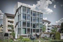 The four-story building, shown from the southwest, is enveloped by a mostly glass façade.