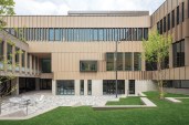 An existing central courtyard (now enclosed by the new addition) is lined in a rainscreen clad in wood-grained FunderMax phenolic panels. The panels were oriented to minimize solar gain, and to signal the pattern of movement along the programmed interior ramps.