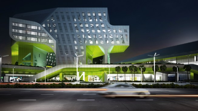 Transitions in fa&ccedil;ade wrapping, from diagonally-oriented punched windows to perforated rainscreen cladding over glazing, blend programmatic volumes for the mixed-use center.