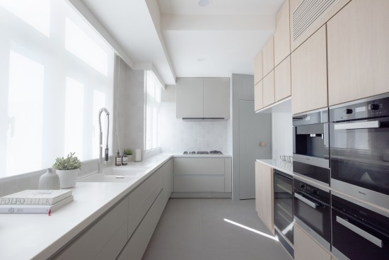 Slithering wooden wall connects living spaces and kitchen, providing concealed storages, appliances and display niches.
