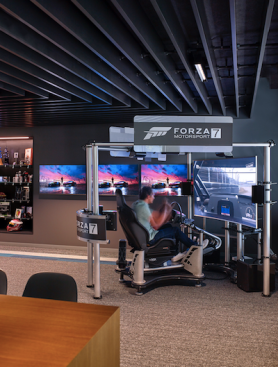 A quick ride up the elevator brings visitors and staff to the vibrant hub space on the third floor, where they can strap into a multi-screen gaming sled for a physical and visual simulation of the optimum racing experience, via the client's latest release.