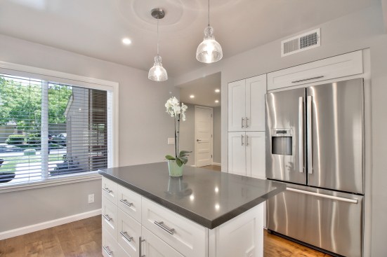 White shaker cabinet, Open space kitchen with quartz counter top. 
Wood flooring 