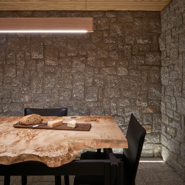 In the granite-lined wine cellar of the day pavilion, the Line Lights pendant fixture in white ash from Matthew McCormick hangs above a custom table by Amos Wood.