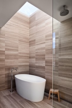 The master bathroom’s limestone walls and floors contrast against the stark-white, freestanding bath and chrome fixtures from Gingers.