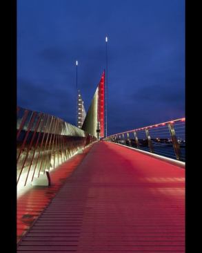 The pedestrian walkway becomes washed in red as the color of the light changes with the opening of the bridge.