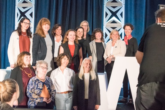Past and current Women’s Leadership Summit planning committee leaders gather for a group photo on the event’s main stage.