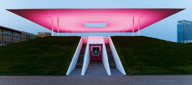 At night, a vivid wash of colored light, in this instance magenta, uplights the underside of the roof plane at Twilight Epiphany, James Turrell’s most recently completed skyspace on the Rice University campus in Houston.