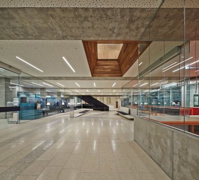 Acoustic ceiling panels help to dampen sound in the stone, glass, and metal-lined foyer. A wood-lined coffer from Timberbuilt gives a glimpse of the main design studio above.