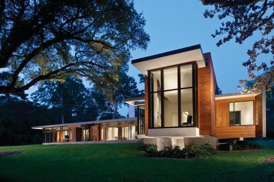 The house's cantilevered elements echo the sheltering angles of the nearby live oaks.