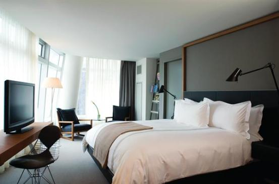 Each guest room features a unique footprint defined by the curved profile of the tower. The clerestory-level lites in the curtain wall are more heavily fritted to help mitigate glare in the rooms when the sun is at its peak. The canted form of a support column is echoed in a ladder bookshelf, holding more of Ortlieb?s beloved volumes.