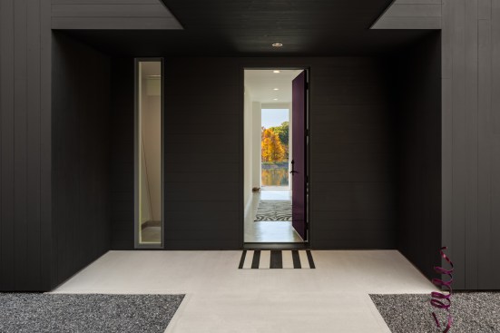 The entry vestibule warmly welcomes guests into the home, while an adjacent fixed window is positioned to allow the clients’ cat to sit and look out. In lieu of exterior landscaping, gravel hardscape was used around the home’s perimeter, functioning as a tick barrier.