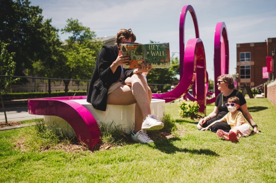 Family sits and reads a book in pARC. 