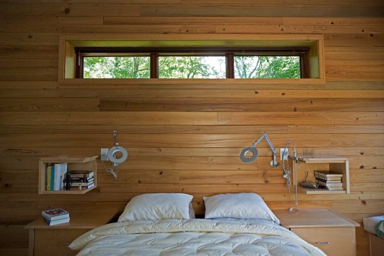 A reclaimed cypress wall in the master bedroom. The architect designed the wall-mounted shelves. 