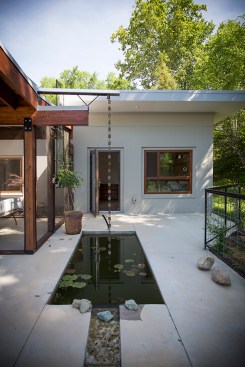 A cantilevered gutter and rain chain lead rain from the roof to a collection pond.
