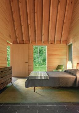 In the bedrooms, the forested site is visible through windows from Marvin Windows and Doors. The simple furnishings include beds from Design Within Reach and dressers from Arbet Design.