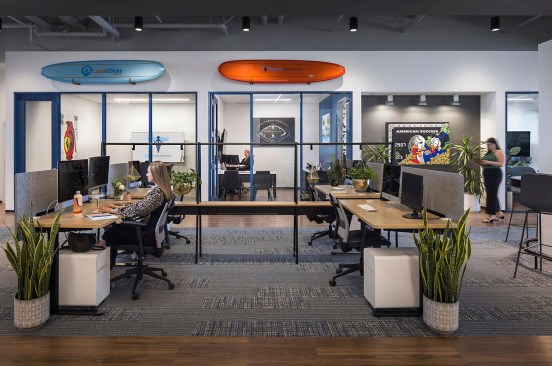 The continued office space features light open concept desks, private modern offices with-floor-length windows, and a high-end gallery wall
