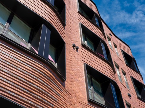 A modern take on the neighborhood’s historic oriels, Willkommen on Vine’s undulating brick wall gloats above a glass storefront, providing residents with privacy and sunlight.