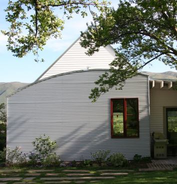At the north elevation, architect John Cottle stuck a gabled roof on two stories and then superimposed a curved roof and galvanized steel fa&ccedil;ade for the adjoining single story, calling to mind both the private houses and smelting kilns of Old Town Basalt.