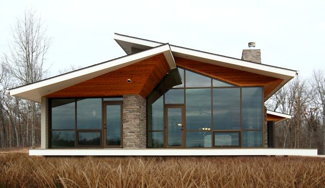 The stained cedar soffit for this home’s roof truss is a warm contrast to the glass fa&ccedil;ade, and its upturned shape makes the roof appear to float above the house. Location: West Plains, Missouri; Architect: Core10 Architecture