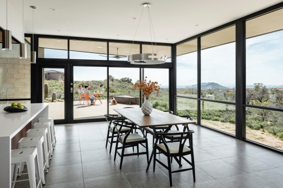 The main dining area is surrounded by floor to ceiling glass.  A 3 panel sliding door systems opens to the outdoor patio beyond.
