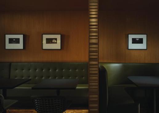The bench seating on the south wall accommodates four two-person tables. Cherry wood panels are illuminated by concealed light fixtures behind the mossy-green leather seat back. Completing the minimal but rich materials palette for the area is the black honed granite that serves as the table tops ? the same material that forms the bar top across the room.