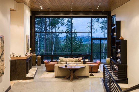 Interior, horizontal, living room at twilight looking out to mountain and forest view, Rosenthal residence, Wilson, Wyoming; Ward + Blake Architects