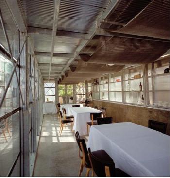 An old bakery conveyor belt undulates above the indoor tables (middle), concealing inexpensive light fixtures. Translucent glass awnings (top) add texture to the rear of the house.