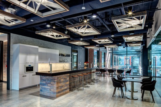 The pantry’s bar symbolically mixes materials to mirror a construction schedule. The island’s timeline starts with real wood block stacks to wood slats and then white Calacatta Venato marble from Architectural Ceramics. Metal encircles the Atrix Polished Granite Slab bar top’s channeled edge. The marble slab also hides the keg and cold brew taps. Their placement corresponds to the time of day – coffee in the morning and a beer in the evening. The custom, acrylic lights sit within an architecturally relevant golden ratio frame and add drama and depth to the exposed ceiling.