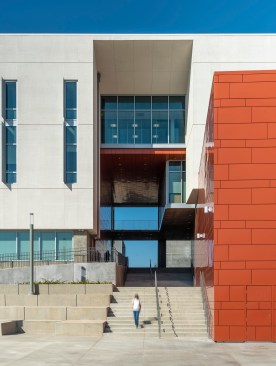 Long and thin, the building is expressed as a perforated bar intersected by a colorful volume, the auditorium, that welcomes the campus community.