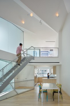 Built of thin steel stringers and treads and lined with mesh guardrails, the staircase from the sixth-floor living area leads to a seventh-floor loft with a bedroom and bathroom.