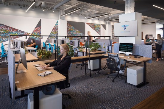The second floor is a dynamic, open concept office space filled with wooden standing desks, exposed high ceilings and an accent wall with inspirational words