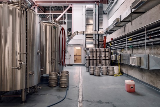 The double-height fermentation hall is lined with concrete floors and the patched original CMU walls, and connected to the dining room via windows. 
