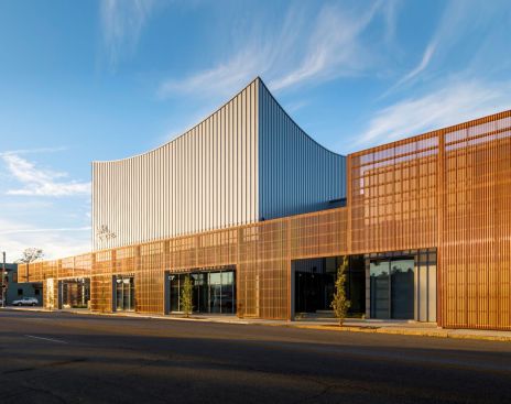 A natural copper street-side perforated metal screen creates a walkway for pedestrians and enhances the dramatic exterior of the Ballet Memphis performance space.