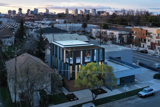 Painted yellow strips, some with embedded LED fixtures, create a dashed pattern over the Sto stucco and cedar façade. 