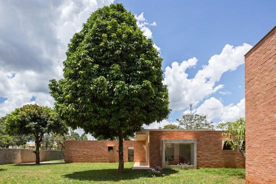 The bedrooms and other private spaces are located at the rear of the house. The architect sited the building to preserve the existing trees, which are protected in Bras&Iacute;lia. A small brick outbuilding (at right) serves double duty as a dog house and a water cistern.