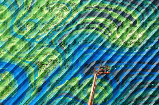Thousands of labyrinthine stripes comprise the swirling motif and ventilated architectural skin.