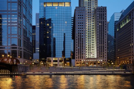 The River Theatre as seen from across the river. The space features illuminated stairs, ramps, and trees.