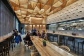 Glowing plywood ceiling illuminated by Type A–lamp pendants above dining area
