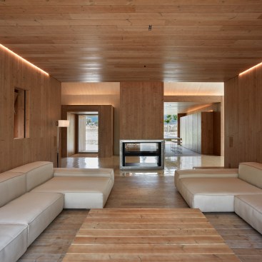 Each of the wood-lined living spaces opens onto a central common area with a bidirectional fireplace that warms the interior during winter months. Mineral-wool insulation helps the structure retain heat in winter and stay cool in summer.