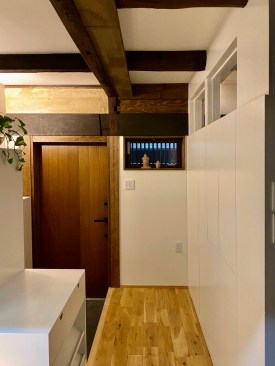 The entry door header and the earth-plastered wall above are the original machiya interior left exposed.