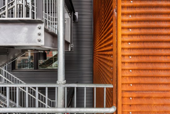 Detail view of egress stair and corrugated Cor-Ten elevator core on street front of building