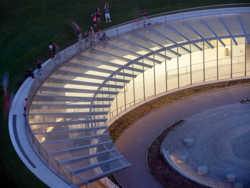 LED downlights integrated into the canopy softly light the curved entry ramps and plaza perimeter, Gateway Arch Museum and Visitor Center