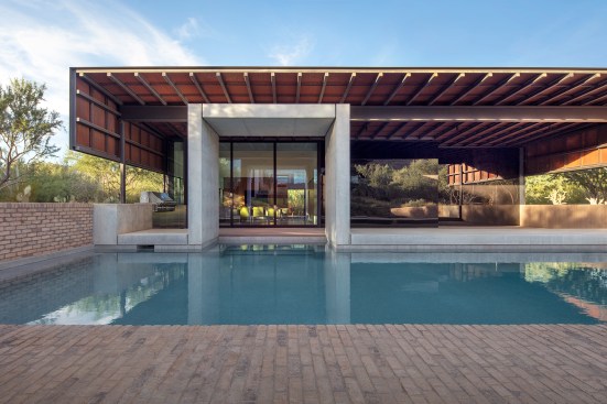 In the pool house, the light wood ceiling and Viracon glazing contrast with a poured-in-place-concrete entrance canopy executed by Concrete Works.