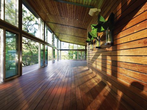 The flexible indoor/outdoor seating area on the second floor is clad on the floor, walls, and ceilings in wood planking that extends outdoors as the decking of the cantilevered balcony. Glass doors allow the seating area to extend out onto the balcony when Houston’s hot, humid climate permits.