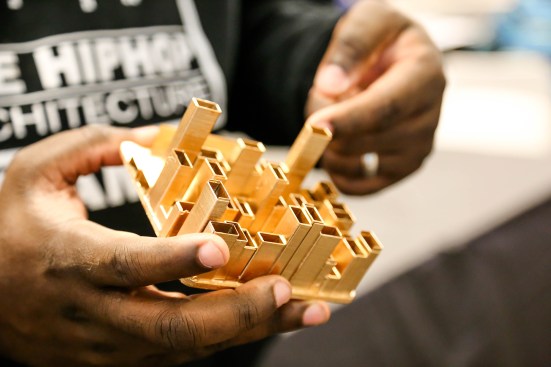 Michael Ford holds a gilded city model created by one of the students. This student "remixed" the city by scrambling the order of the words of the verse to create a more dynamic skyline.